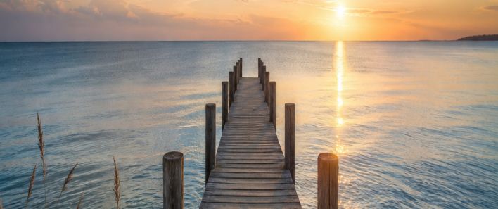 Holzsteg auf einem ruhigen See bei Sonnenuntergang